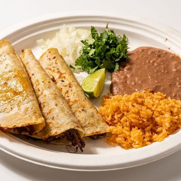 Three golden-brown tacos with shredded meat, rice, refried beans, cilantro, onions, and a lime wedge.