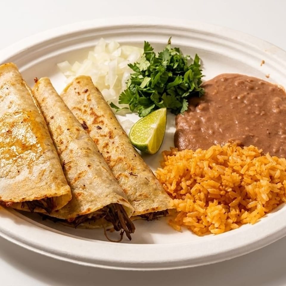 Three golden-brown tacos with shredded meat, rice, refried beans, cilantro, onions, and a lime wedge.