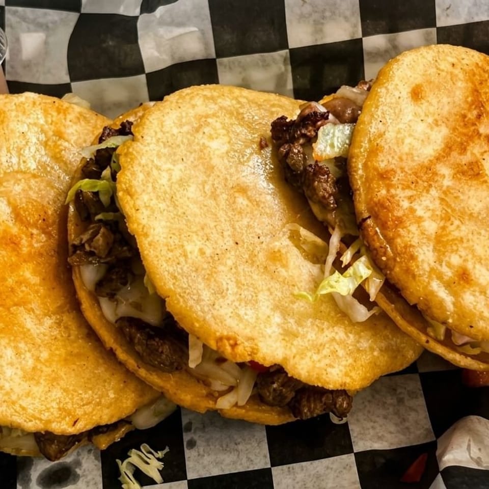 Three golden-fried tacos filled with meat and lettuce, served with a side of salsa.